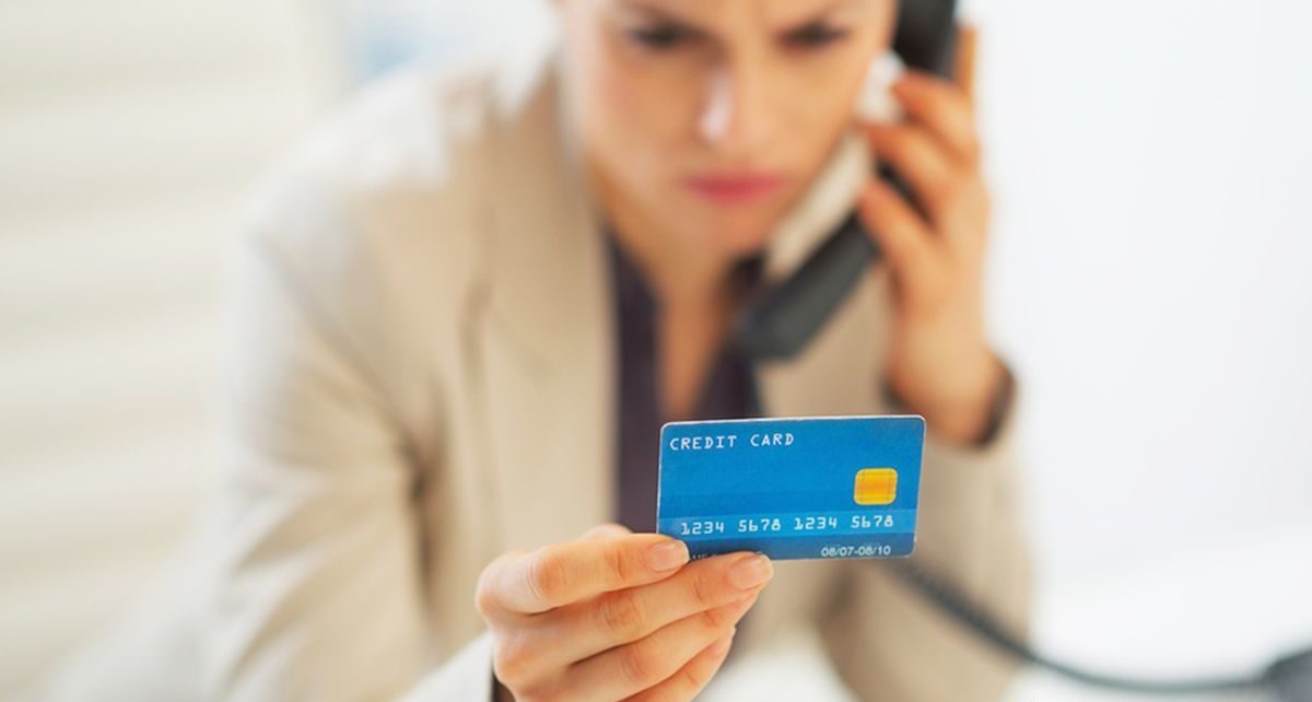 Closeup on business woman with credit card talking phone in office